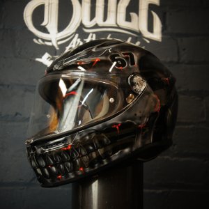 Black motorcycle helmet with realistic skull jaw design featuring exposed teeth, red glowing accents and dark horror-themed airbrush artwork