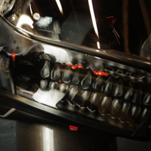 Black motorcycle helmet with detailed grey skull design featuring red glowing eyes and exposed teeth jaw airbrush artwork